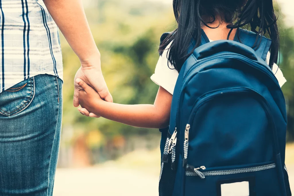 Mom holding daughters hand on way to school