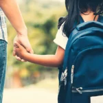 Mom holding daughters hand on way to school