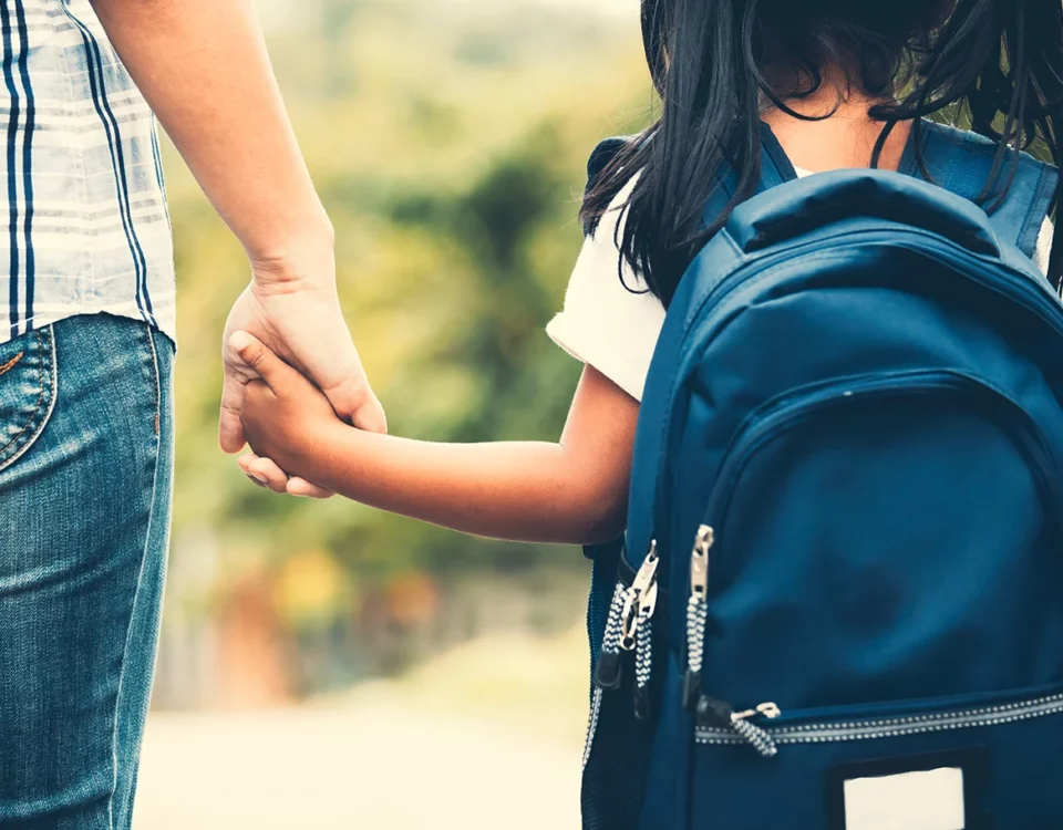 Mom holding daughters hand on way to school